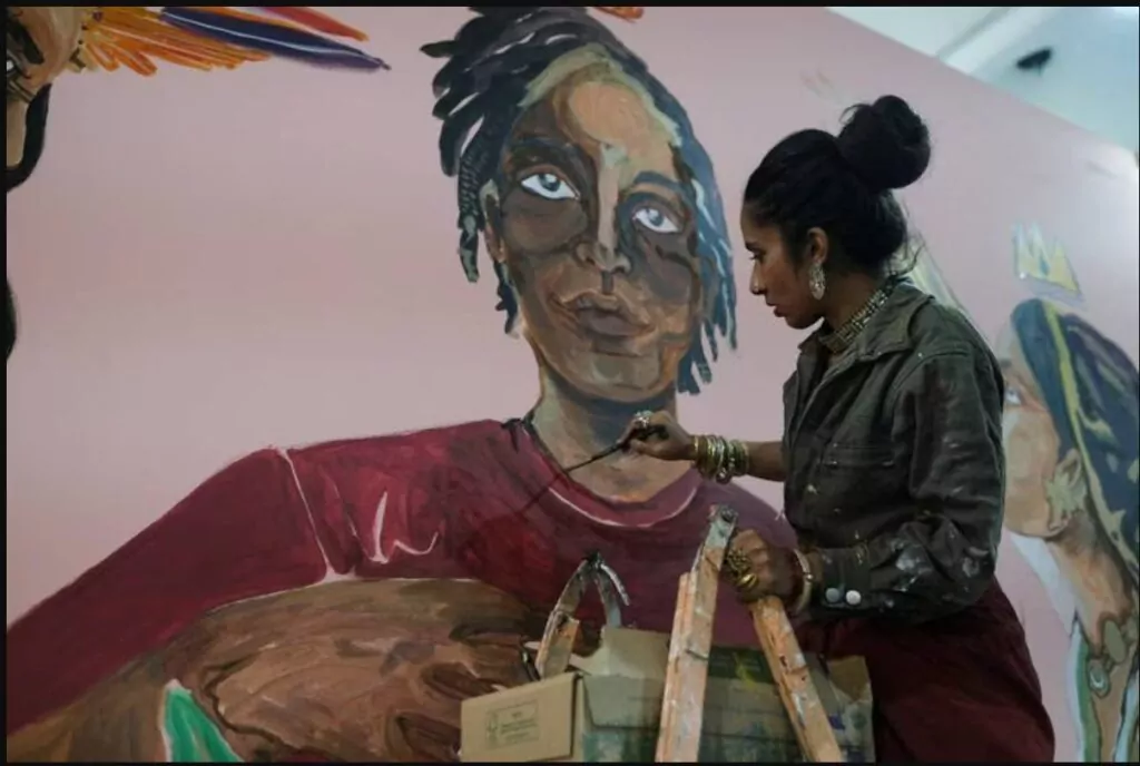 Shilo Shiv Suleman of India, founder of Fearless Collective, paints on a wall during COP27. 