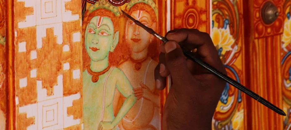 a close up shot of an artist's hand as they paint a Kerala Mural Painting.